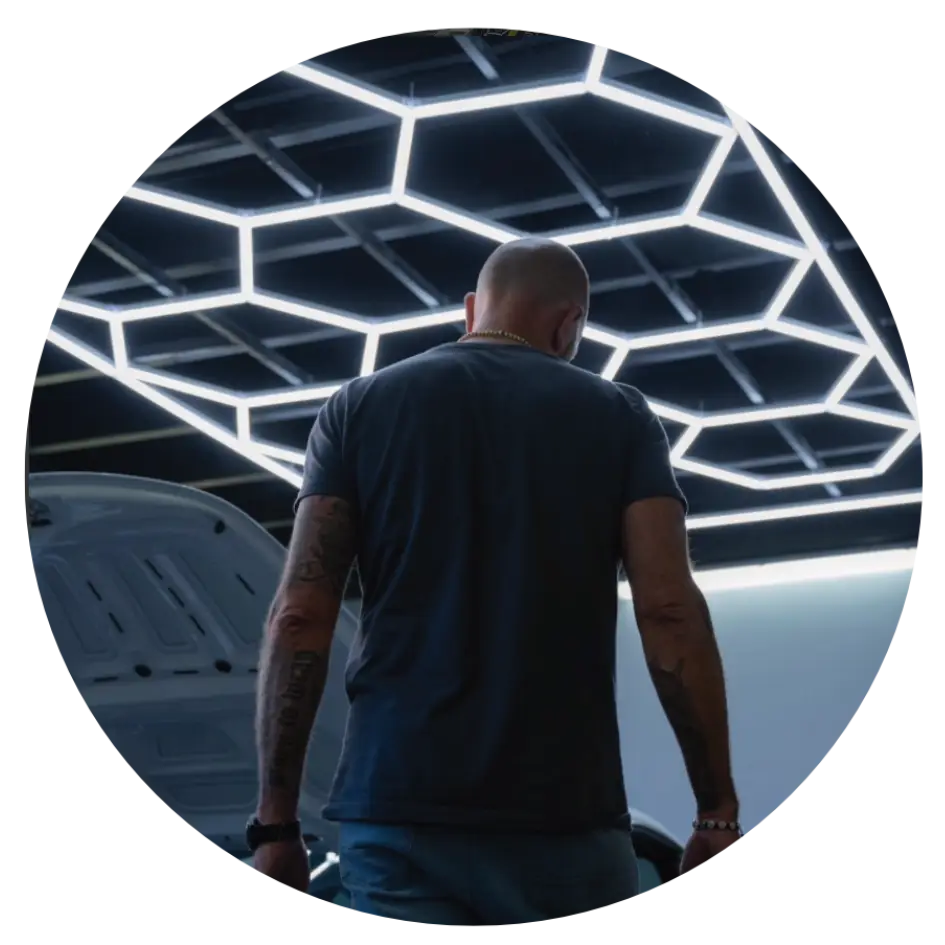 Custom hexagonal LED ceiling grid lighting matrix by OZ Lighting, installed at the Folien-Xtreme vehicle wrapping and car detailing workshop in Villach, Austria, providing shadow-free precision illumination.