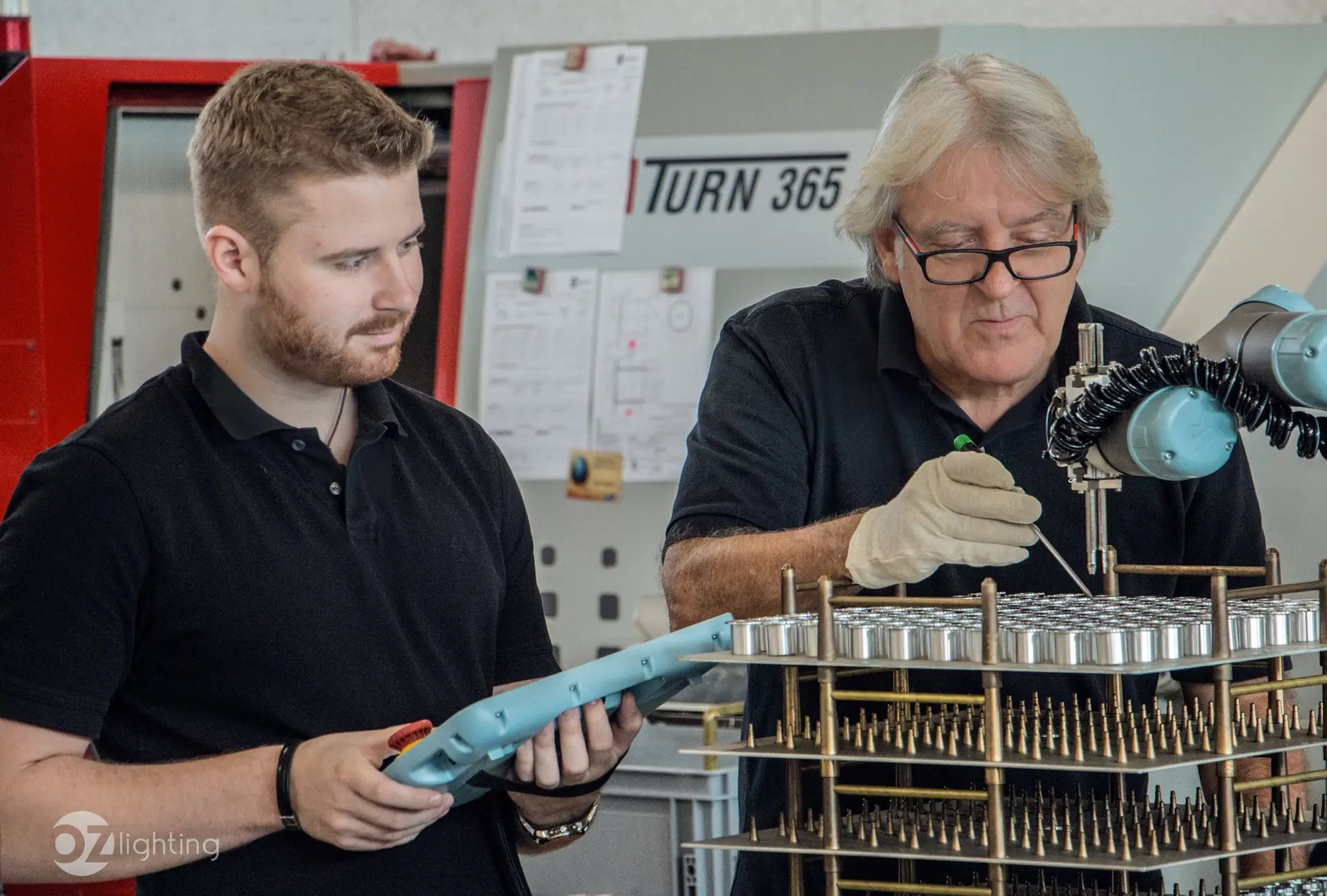 Thomas und Josef bei der computergestützten CNC-Fertigung und robotergestützten Qualitätsprüfung von maßgeschneiderten Lichtkomponenten für OZ Lighting. Das Foto zeigt die präzise Steuerung moderner Zerspanungstechnik und industrieller Automatisierung im hauseigenen Maschinenpark für nachhaltiges Lichtdesign.
