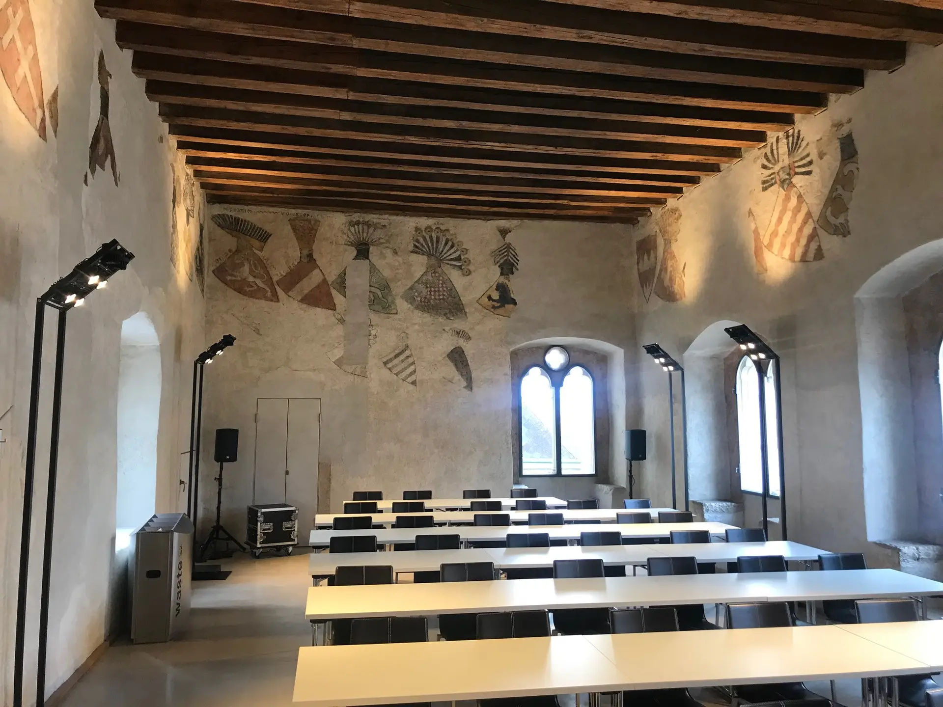 Professionelle Ausstellungs- und Veranstaltungsbeleuchtung von OZ Lighting im historischen Wappensaal Krems. Freistehende, minimalistische LED-Fluter-Stelen illuminieren die mittelalterlichen Deckenbalken und Wandfresken absolut blendfrei und materialschonend, perfekt abgestimmt auf die strengen Denkmalschutz-Vorgaben für moderne Seminarräume.